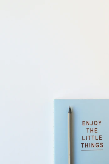 a notebook with the words enjoy the little things written on it, trending on unsplash, analytical art, pale blue, ultra minimalistic, pencil, happiness