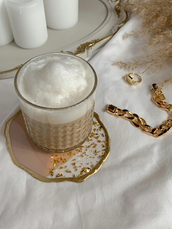 a close up of a cup of coffee on a table, inspired by Hedi Xandt, instagram, pearls and gold chains, vanilla smoothie explosion, soft pads, detailed product image