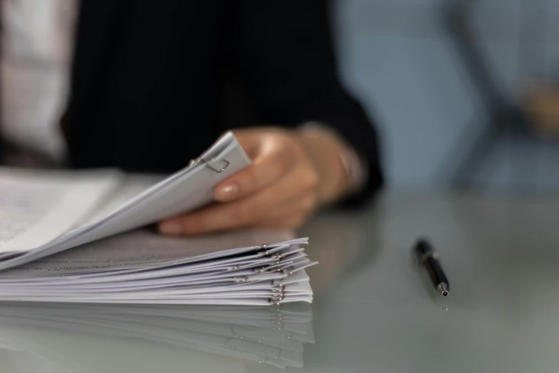 a person sitting at a table with papers and a pen, stacked image, opening shot, detailed -4, fan favorite