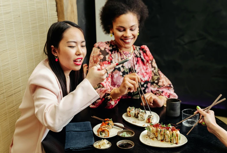 a group of women sitting at a table eating sushi, by Julia Pishtar, trending on unsplash, pretty samurai with afro, woman holding another woman, dumplings on a plate, profile image