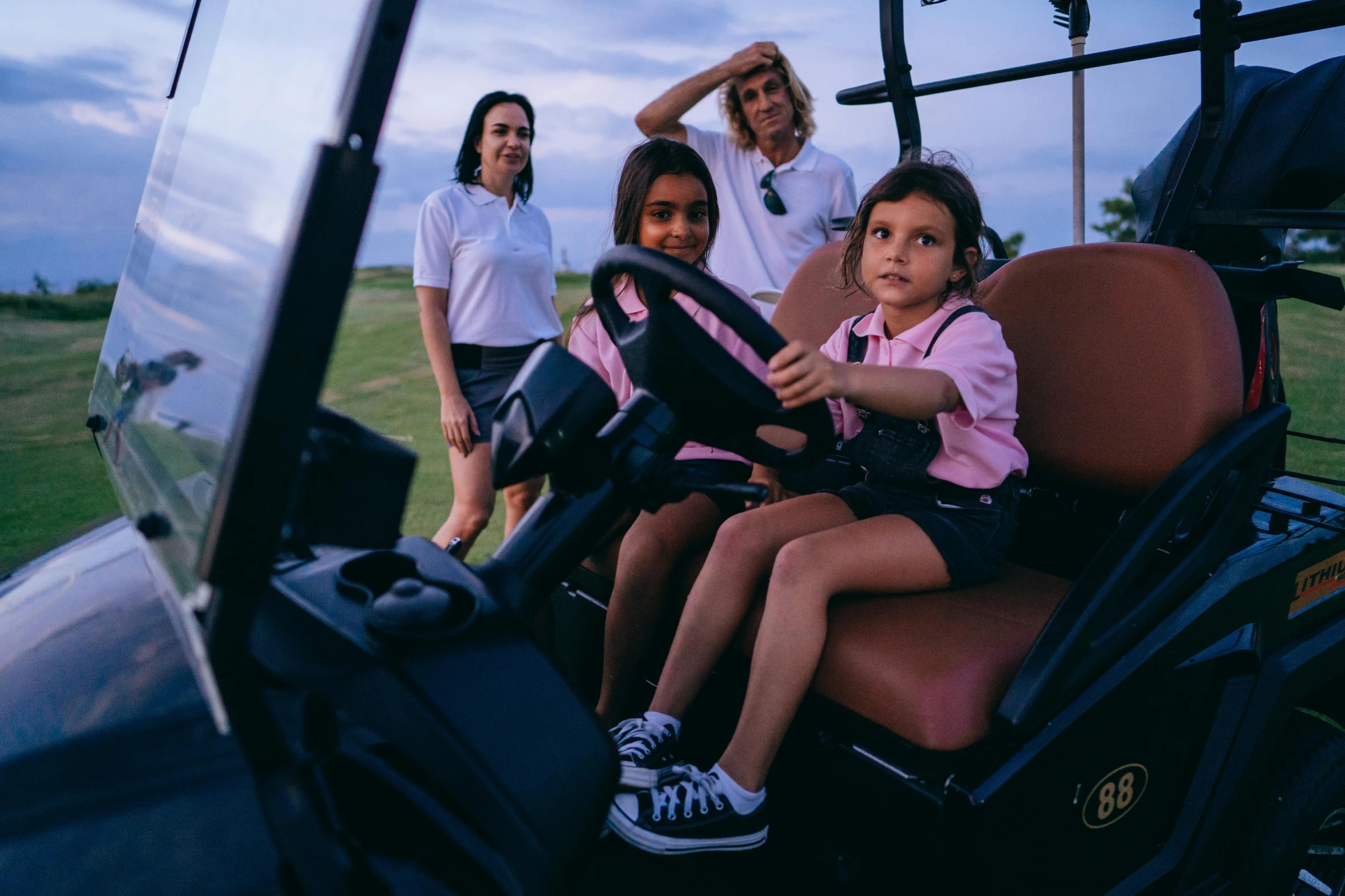 a little girl sitting in the driver's seat of a golf cart, pexels contest winner, happening, alena aenami and lilia alvarado, uniform off - white sky, a group of people, avatar image