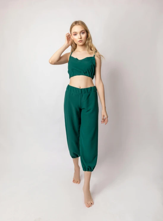 a woman wearing green pants and a cropped top, an album cover, by Louisa Puller, cottagecore!! fitness body, ( ( dark green, sleepwear, short puffy pants