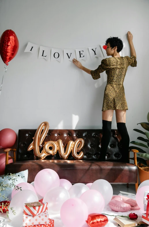 a woman standing on top of a couch in a living room, by Julia Pishtar, pexels, party balloons, i love you, detailed letters, decorations