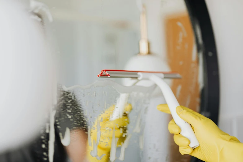 a person in yellow gloves cleaning a mirror, pexels contest winner, spray brush, background image, profile image, freezing