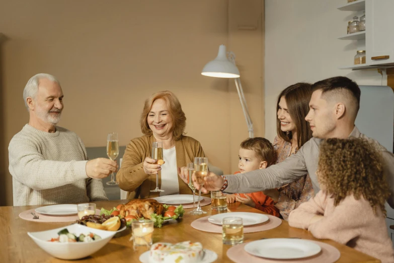a group of people sitting around a wooden table, holding a glass of wine, profile image, families playing, wearing festive clothing