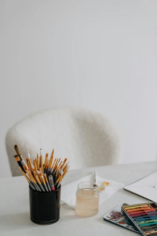 a laptop computer sitting on top of a white desk, a minimalist painting, trending on pexels, visual art, holding paintbrushes, carefully crafted, painting of an undercover cup, white backdrop