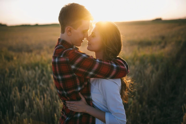 a couple kissing in a field at sunset, pexels, romanticism, lovingly looking at camera, hug, good looking, boy and girl