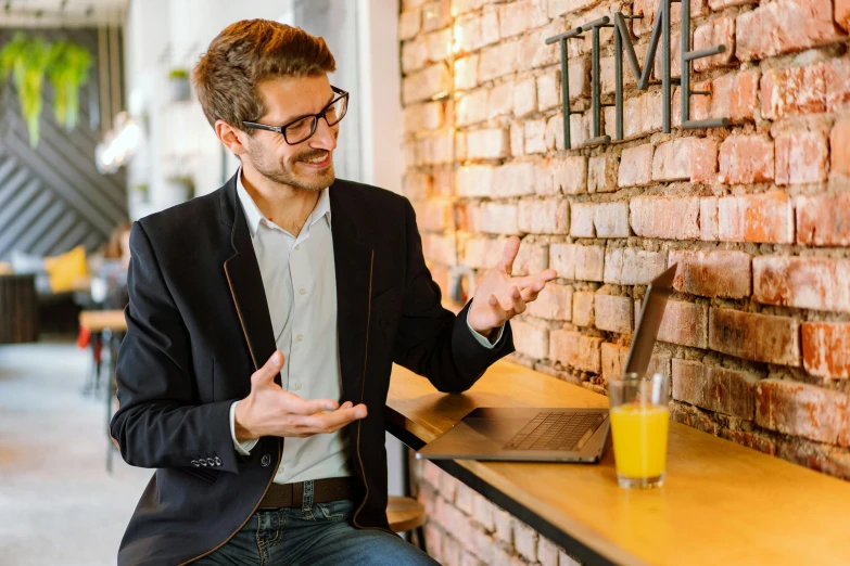 a man standing in front of a brick wall, sitting at a computer, professional comercial vibe, tia masic, excitement