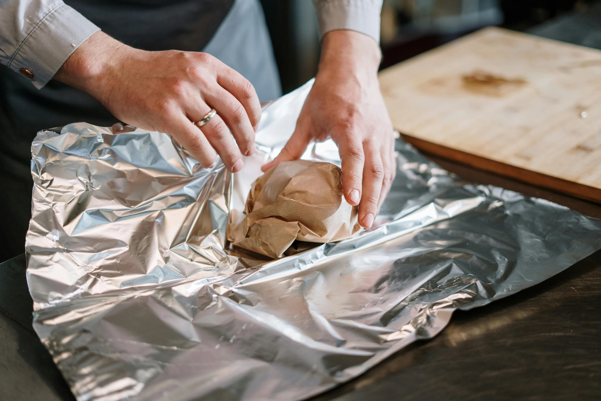 a person putting a piece of bread on a piece of tin foil, by Julia Pishtar, pexels contest winner, process art, steamed buns, brown paper, peter dutton as a potato, thumbnail