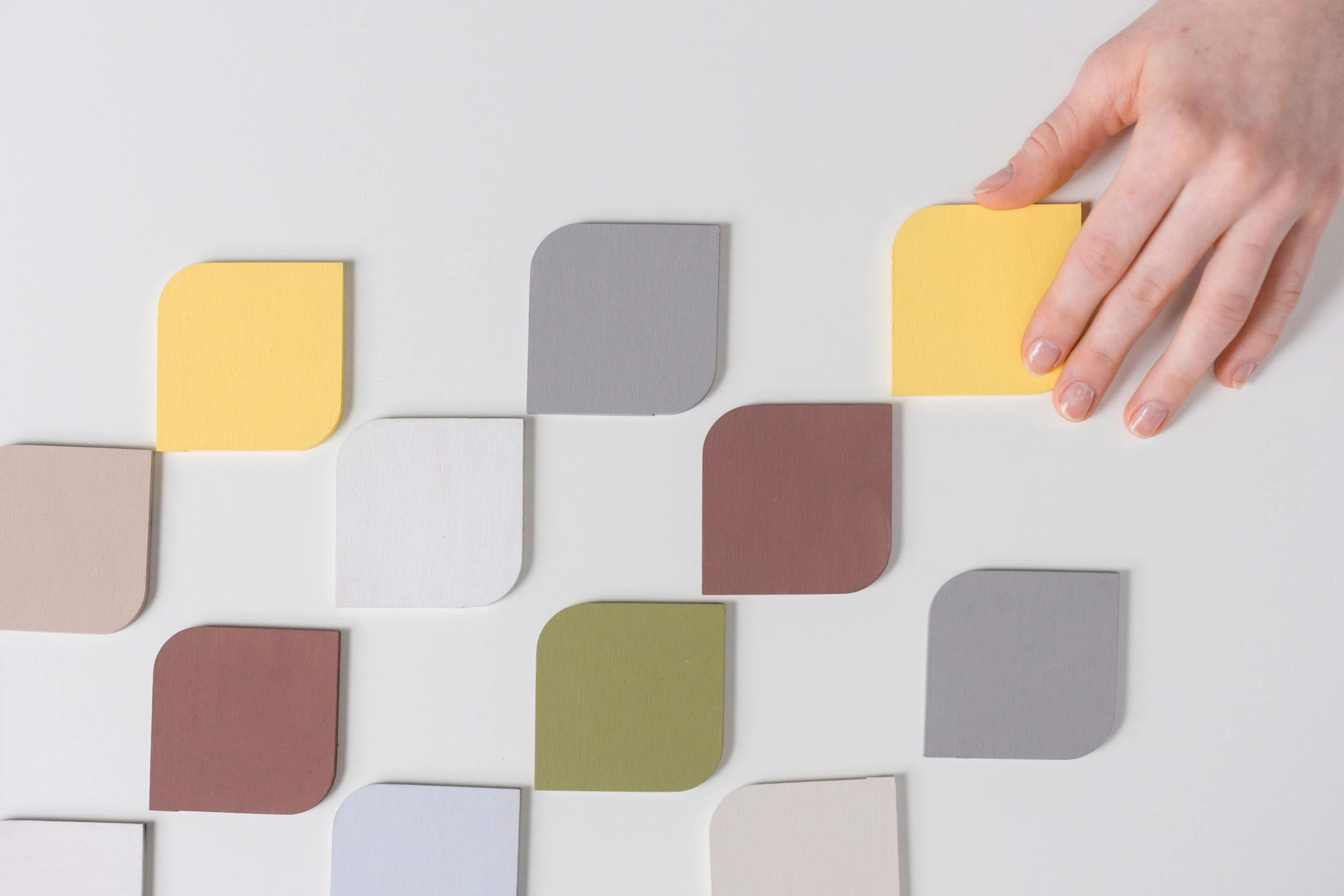 a close up of a person holding a piece of paper, inspired by Frederick Hammersley, trending on unsplash, interactive art, in muted colours, squares, turning yellow, on grey background