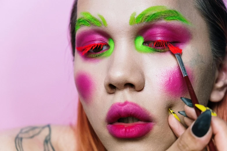 a close up of a person with pink and green makeup, an album cover, inspired by Russell Dongjun Lu, holding paintbrushes, lashes, well drawn, non binary model