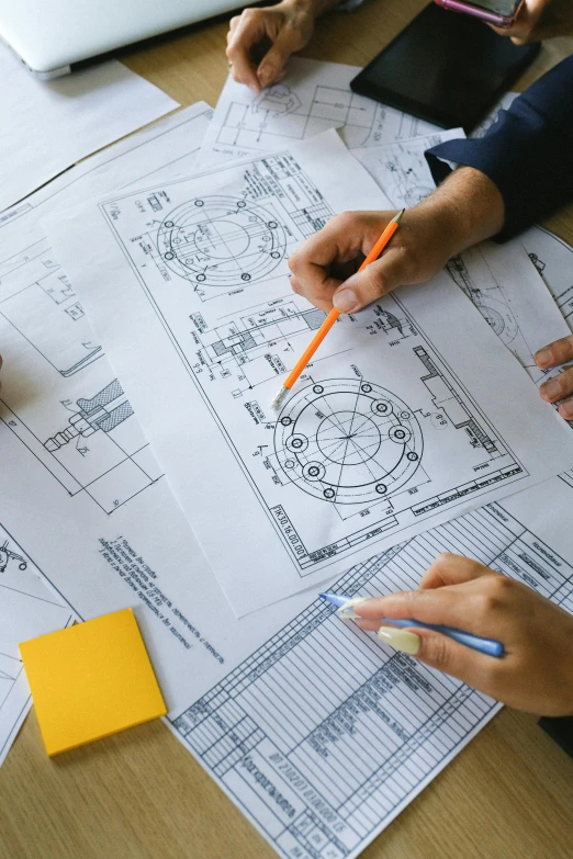 a group of people sitting at a table working on blueprints, a detailed drawing, by Oskar Lüthy, trending on unsplash, diagram specifications notations, medium close up shot, hydraulics, high angle shot