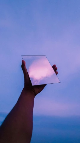 a person holding up a mirror with the sky in the background, an album cover, pexels contest winner, aestheticism, gradient light purple, technologies, transparent glass, cloud