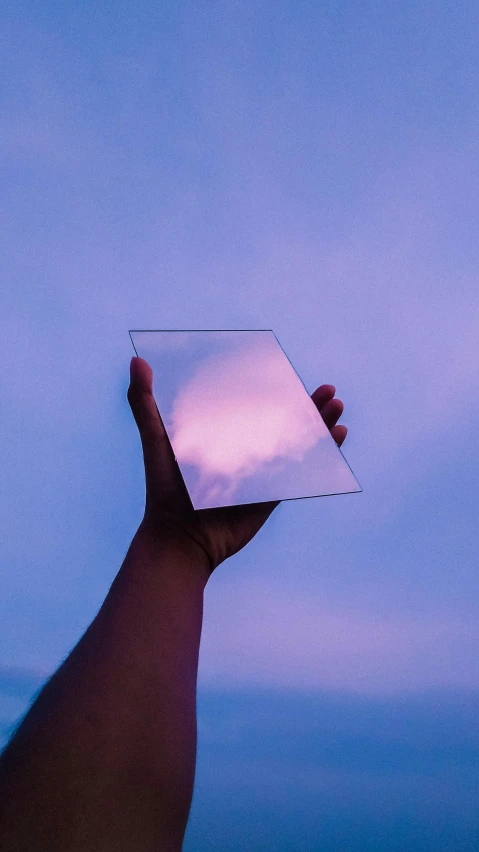 a person holding up a mirror with the sky in the background, an album cover, pexels contest winner, aestheticism, gradient light purple, technologies, transparent glass, cloud