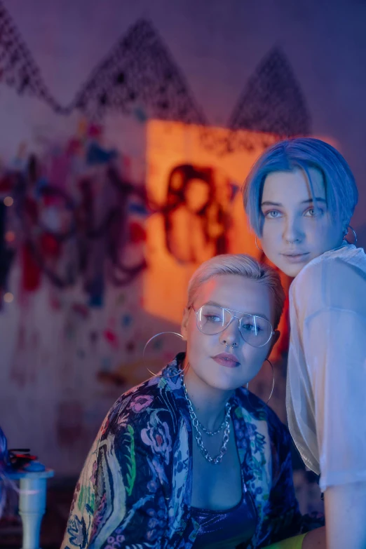 two people standing next to each other in a room, an album cover, inspired by Elsa Bleda, trending on pexels, girl with blue hair, lesbian, colorful lenses, (night)