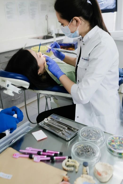 a woman getting her teeth examined by a dentist, happening, sitting on a lab table, innovation, grey, thumbnail