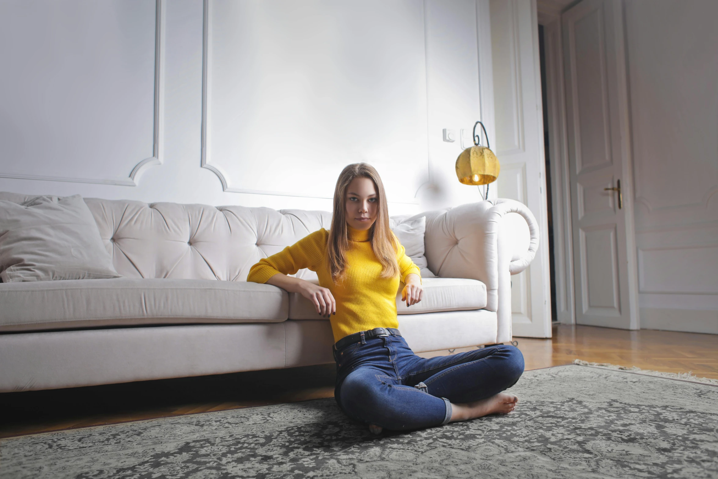 a woman sitting on the floor in front of a couch, inspired by Sarah Lucas, pexels contest winner, arabesque, yellow carpeted, handsome girl, anna nikonova aka newmilky, the living room