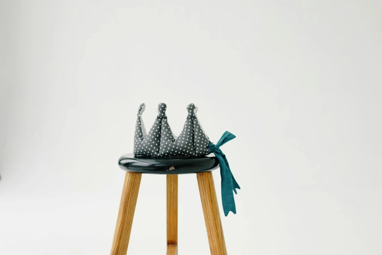 a pair of shoes sitting on top of a wooden stool, wearing a paper crown, dark grey, made of dots, high quality upload