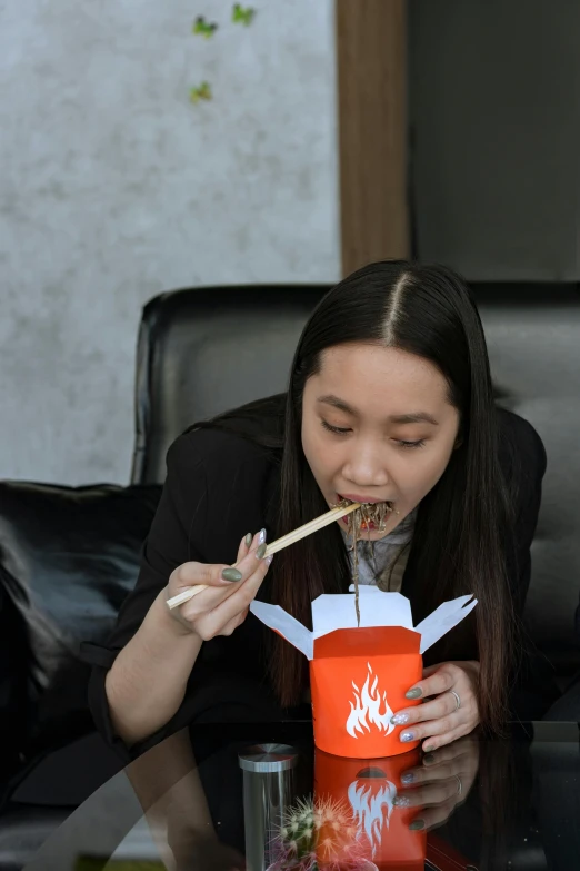 a woman sitting at a table eating with chopsticks, firey, fast food review, sitting in a chair, jakarta