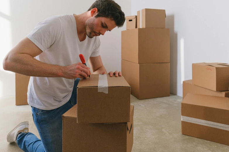 a man sitting on the floor next to a pile of boxes, by Tom Bonson, pexels contest winner, package cover, australia, leaving a room, crafting