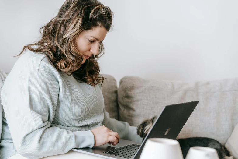 a woman sitting on a couch using a laptop, trending on pexels, avatar image, woman with braided brown hair, bottom angle, profile image