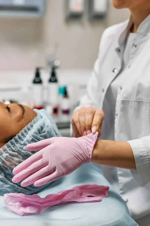 a close up of a person in a hospital bed, wearing gloves, skincare, woman holding another woman, pink