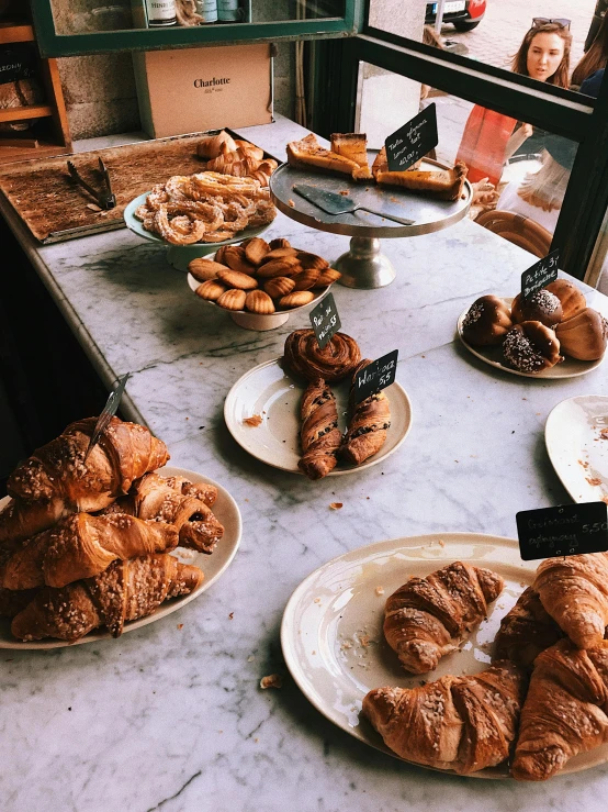 a table topped with plates of croissants and pastries, by Nina Hamnett, trending on unsplash, grainy quality, thumbnail