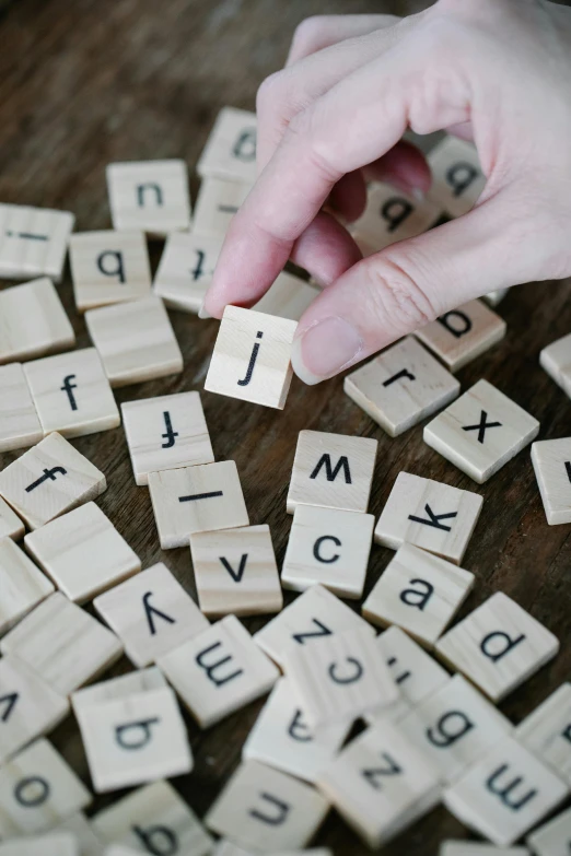 a person playing with scrabbles on a table, by Julian Allen, pexels, letterism, square, on wood, made of glazed, thumbnail