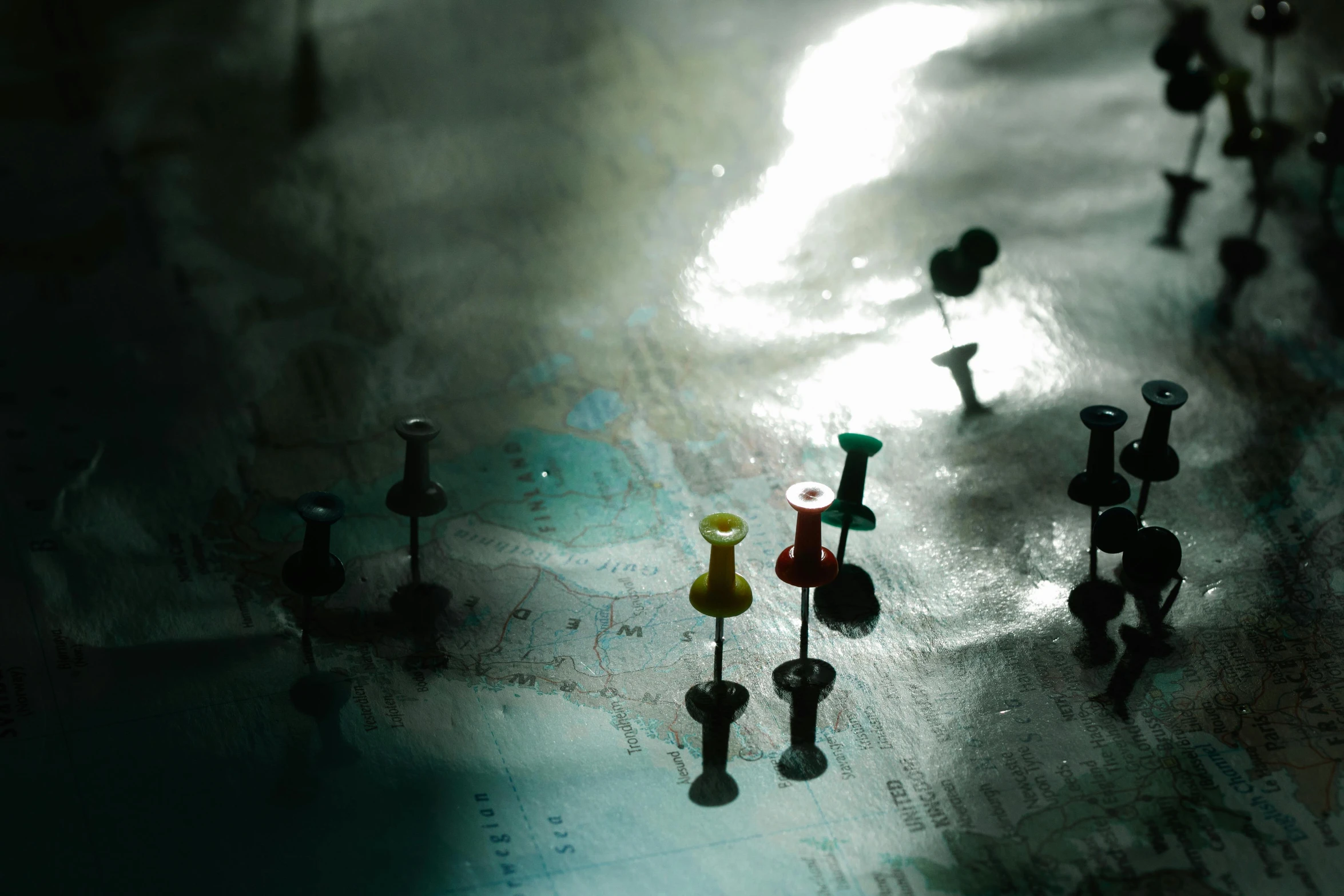 a bunch of pins sitting on top of a map, unsplash, wet reflections, spotlight, overcast mood, in 2 0 1 2