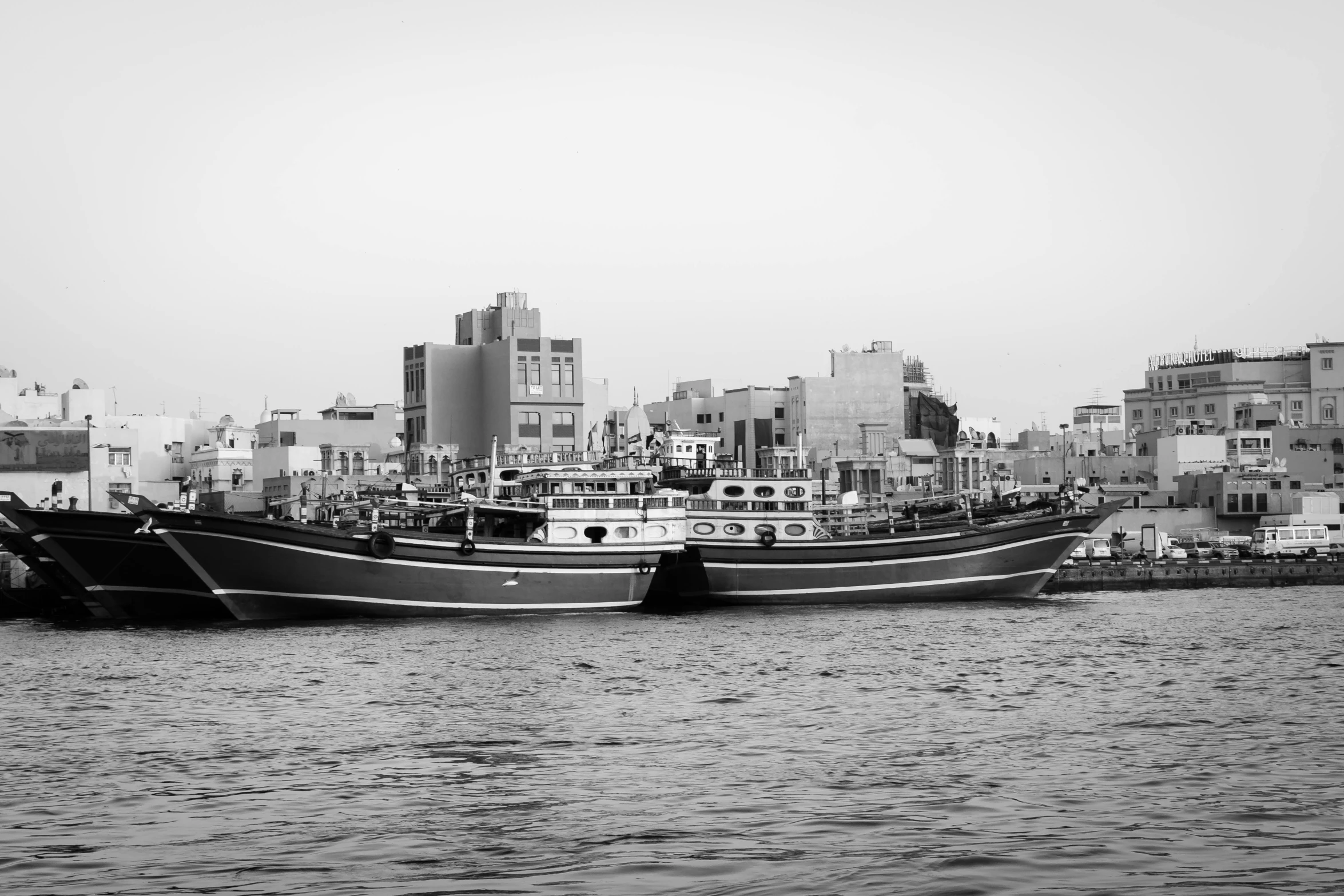 a black and white photo of two boats in the water, a black and white photo, by Ahmed Yacoubi, hurufiyya, in the middle of the city, modern high sharpness photo