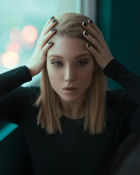 a woman sitting in front of a window with her hands on her head, inspired by Elsa Bleda, trending on pexels, surrealism, blonde hair and large eyes, portrait sophie mudd, wearing black clothes, desaturated color