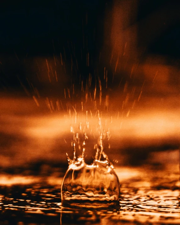 a glass filled with water sitting on top of a table, by Daniel Lieske, pexels contest winner, holography, raining fire, golden hour closeup photo, grainy photograph, sculpture made of water