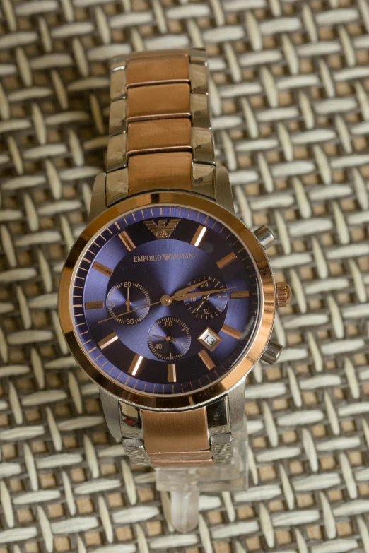 a close up of a watch on a table, inspired by Caesar Andrade Faini, pexels, armani, gold and blue, rose gold, casually dressed