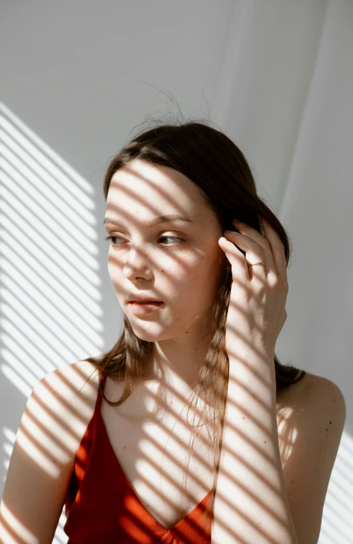 a woman in a red dress standing in front of a window, inspired by Elsa Bleda, trending on pexels, soft shadows on the face, striped, portrait sophie mudd, the sun reflecting on a window