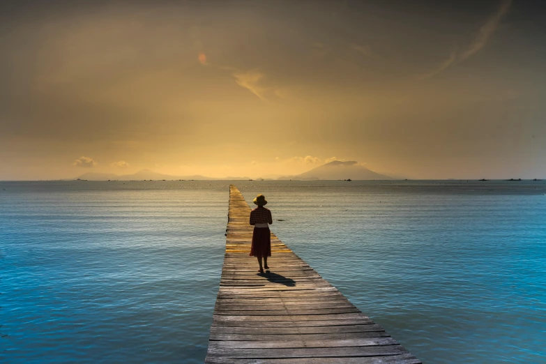 a person standing on a pier in the middle of the ocean, by Eglon van der Neer, pexels contest winner, late afternoon, indonesia, woman, on the path to enlightenment