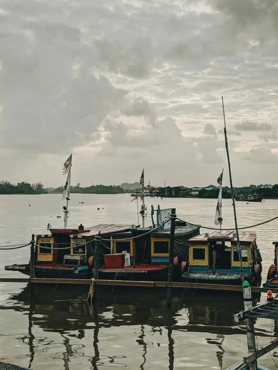 a group of boats sitting on top of a body of water, a picture, pexels contest winner, sumatraism, overcast skies, steamboat willy, set on singaporean aesthetic, next to a river