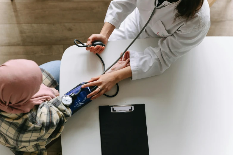a woman using a stethoscope to check a child's blood pressure, a picture, pexels contest winner, sitting on a table, wide screenshot, whealan, small in size