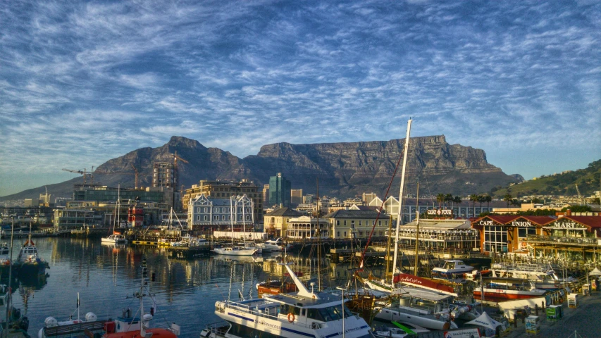 a harbor filled with lots of boats next to a mountain, by Tom Wänerstrand, pexels contest winner, hurufiyya, royal cape, city in the background, avatar image, beautiful late afternoon