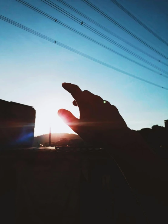 a person holding a cell phone up to the sun, instagram post, sun and shadow over a city, raised hand, photography]