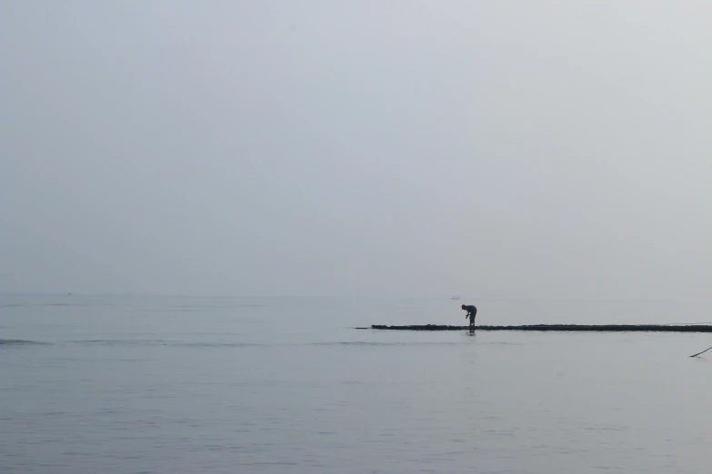 a man riding a surfboard on top of a body of water, by Jan Rustem, minimalism, zezhou chen, gray fog, single long stick, seaview