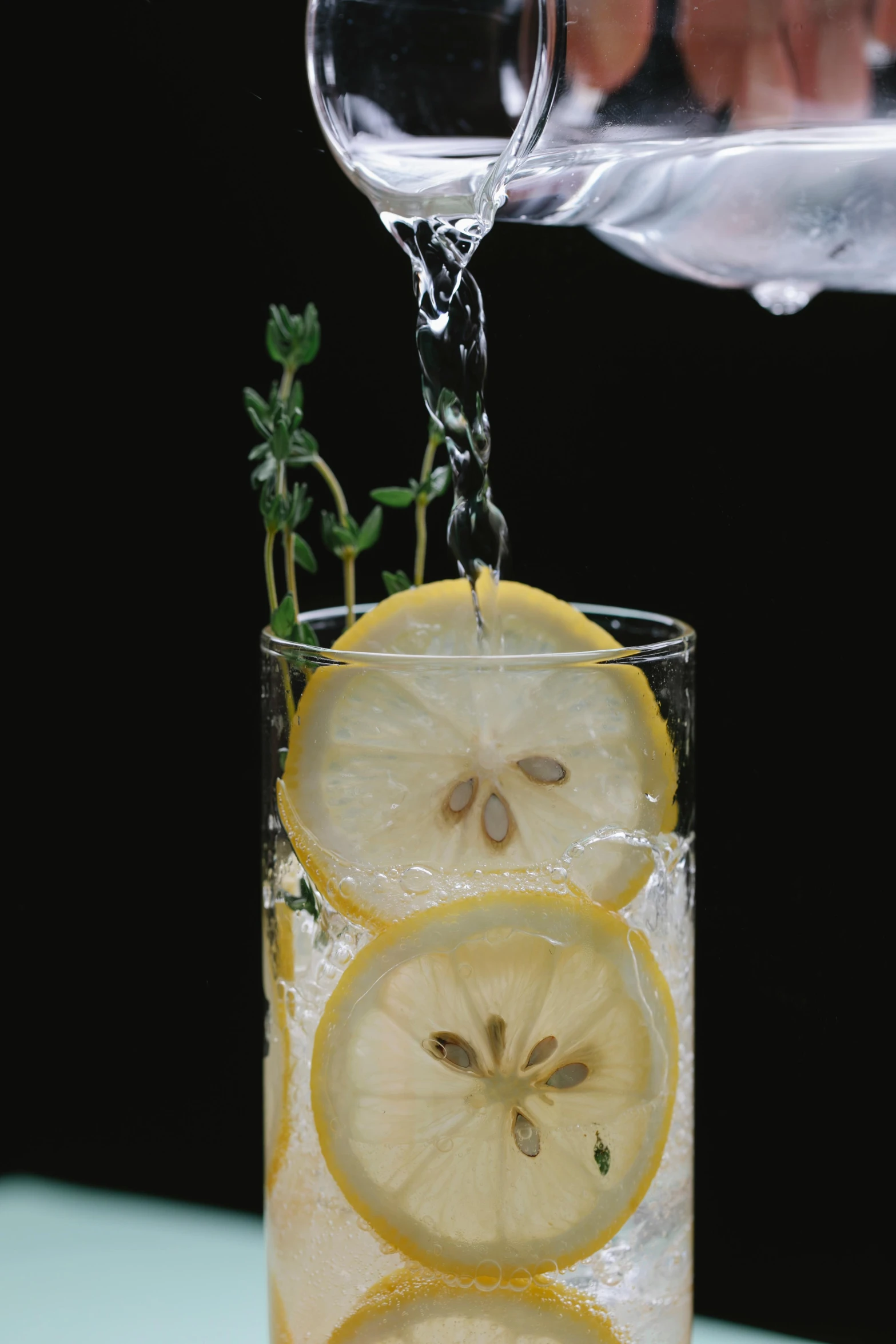 a person pouring water into a glass filled with lemon slices, pexels, renaissance, ivy's, with a black background, promo image, stacked image