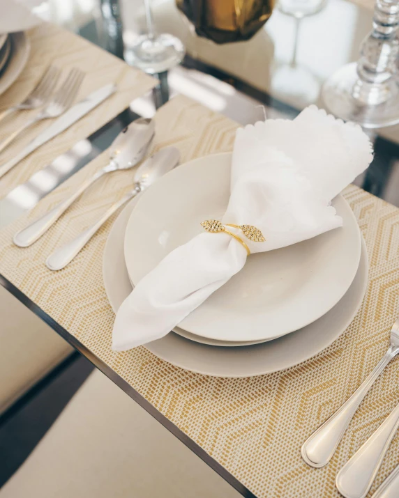 a close up of a table setting with silverware, white and gold robes, pair of keycards on table, angled, patterned