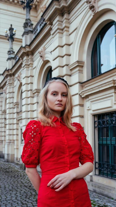 a woman in a red dress standing in front of a building, inspired by Louisa Matthíasdóttir, pexels contest winner, red elegant shirt, in style of terry richardson, square, russian girlfriend