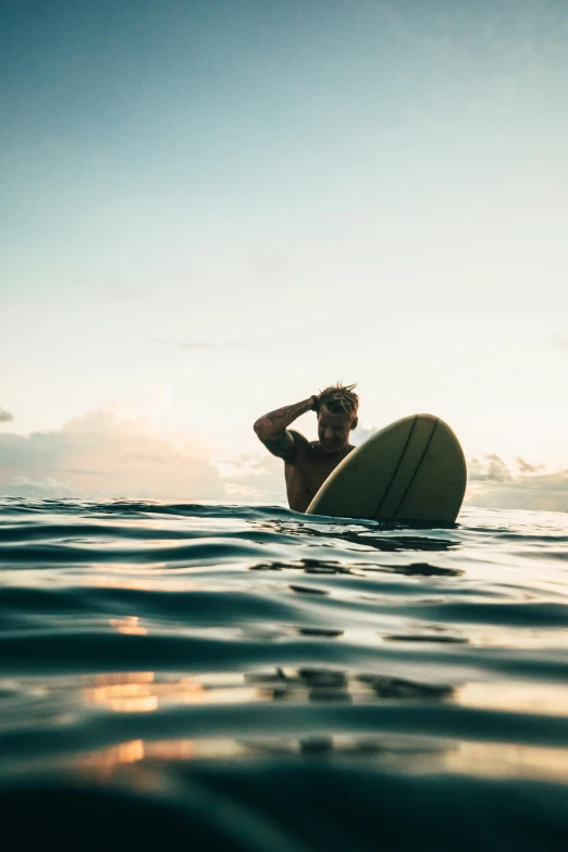 a man sitting on top of a surfboard in the ocean, on the ocean