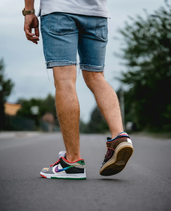 a man riding a skateboard down a street, inspired by Okuda Gensō, trending on pexels, renaissance, denim shorts, sneaker photo, thumbnail, multi colored