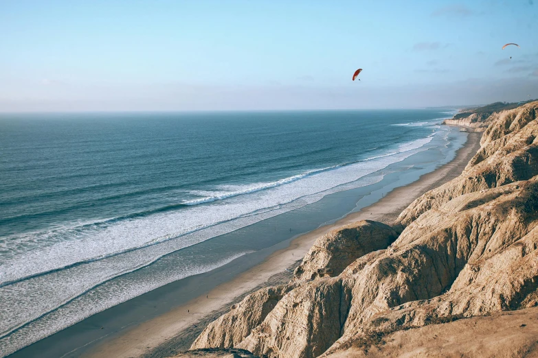 a person flying a kite on top of a sandy beach, by Daniel Lieske, pexels contest winner, coastal cliffs, hollister ranch, avatar image