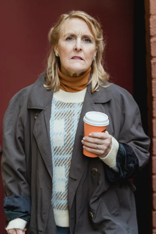 a woman is holding a cup of coffee, a portrait, inspired by Ruth Deckard, shutterstock, photorealism, wearing jacket, 5 5 yo, sidewalk, concerned