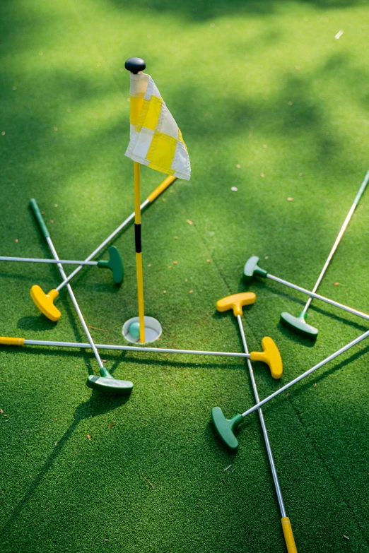 a group of golf clubs sitting on top of a green field, toys, yellow and green, square, thumbnail