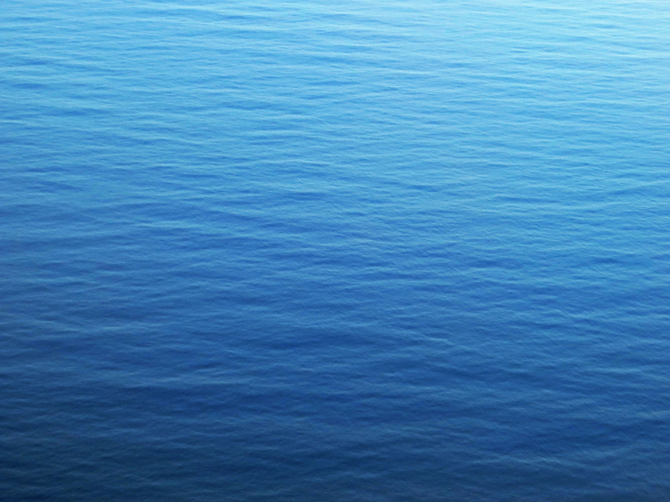 a boat floating on top of a large body of water, an album cover, unsplash, minimalism, deep blue sea color, ((blue)), ripples, ignant