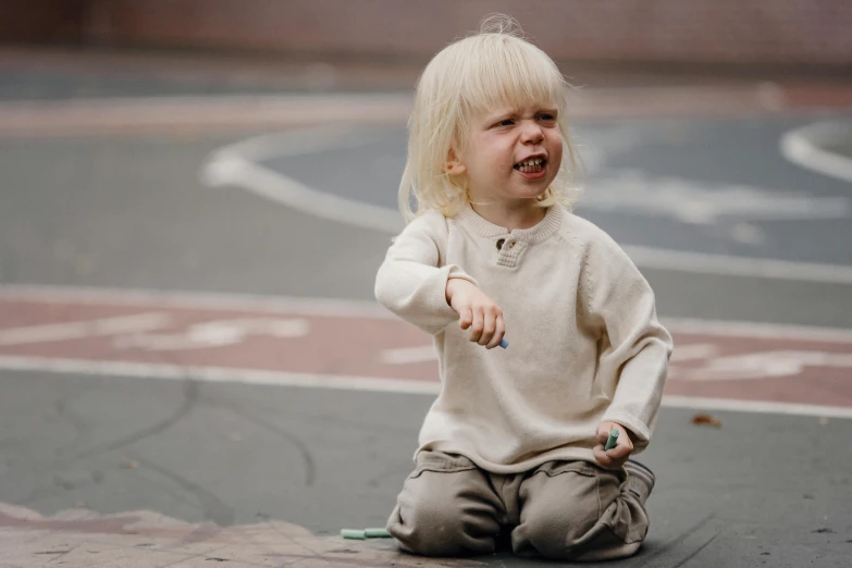 a little girl sitting on the ground with a toothbrush in her mouth, by Attila Meszlenyi, pexels contest winner, frustrated expression, blond boy, in a square, chalked